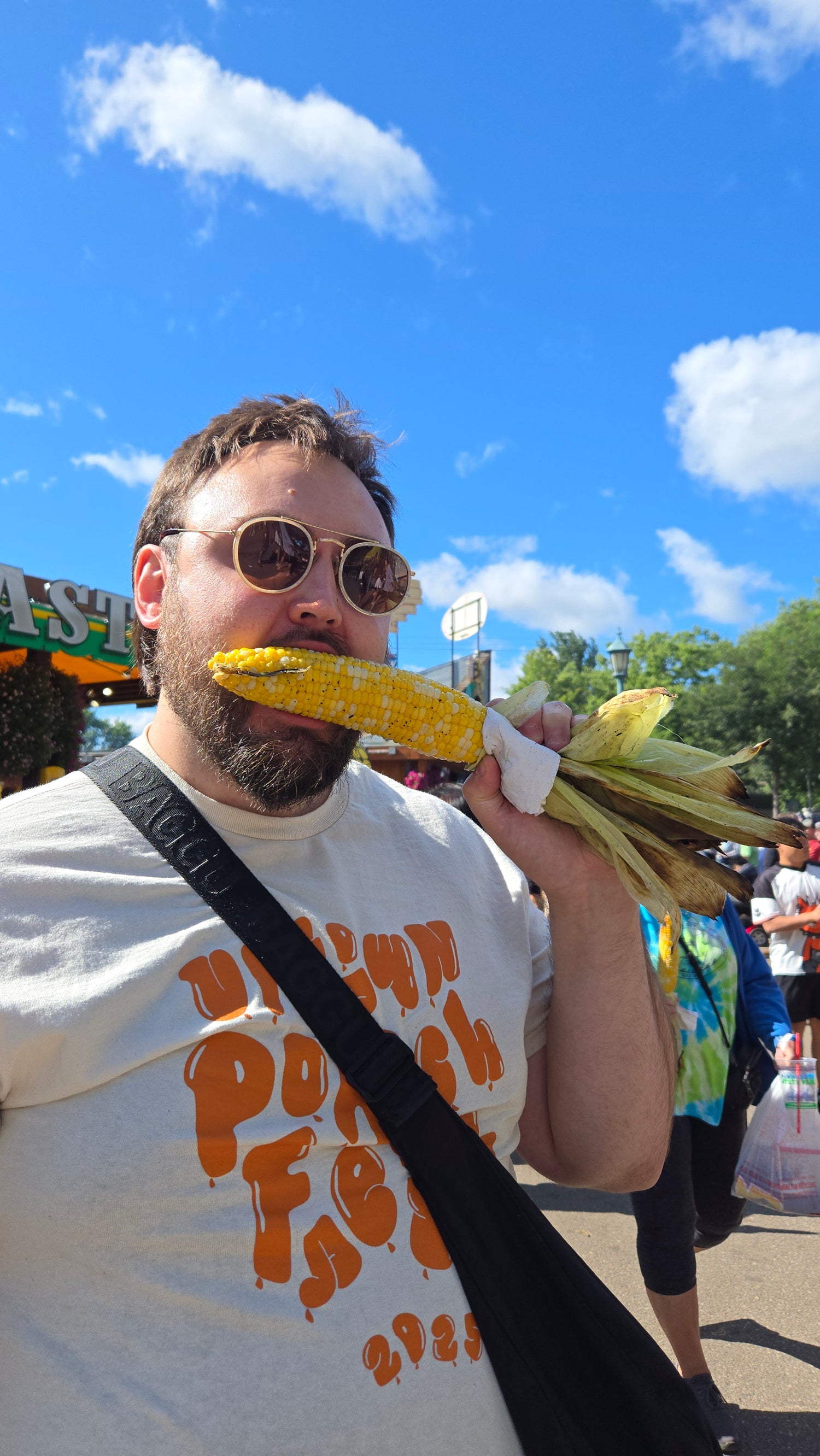 A person (Ty) eating corn on the cob against a blue sky background (decorative)